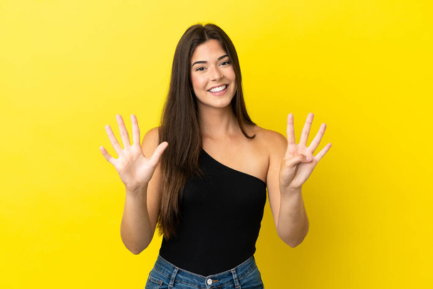 Молода бразилька, відокремлена на жовтому фоні, рахує дев "ять пальцями. - Фото, зображення
