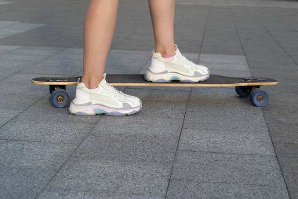 Close up of woman skateboarder legs skateboarding outdoor - Foto, Imagen