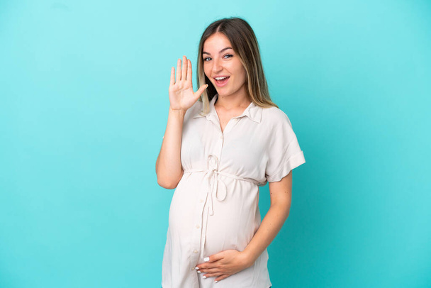 Giovane donna rumena isolata su sfondo blu incinta e urlando - Foto, immagini