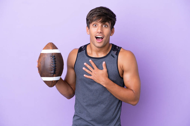 Young man playing rugby isolated on purple background surprised and shocked while looking right - Photo, Image