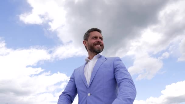 glücklicher bärtiger Mann in Jacke mit Armbanduhr auf Himmelshintergrund, Männermode - Filmmaterial, Video
