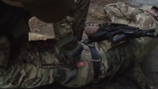 Médico de combate aplicando torniquete al soldado, llevando botiquín de primeros auxilios - Metraje, vídeo
