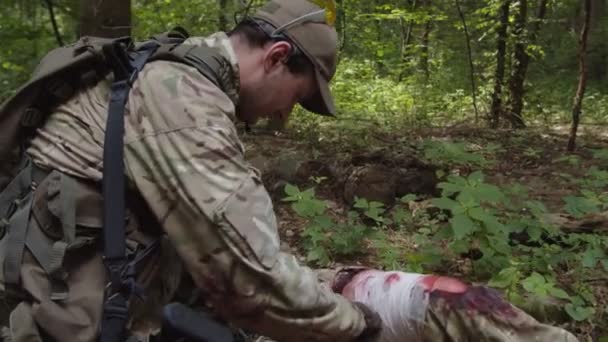 Medyk wojskowy zapewniający leczenie nagłe rannemu żołnierzowi na zewnątrz - Materiał filmowy, wideo