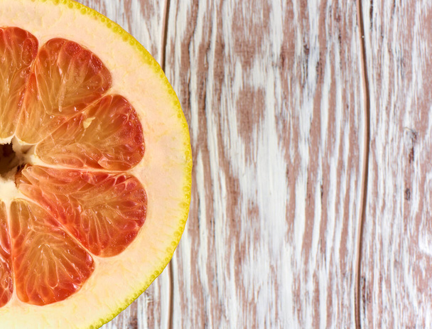 Red grapefruit half on a wooden background with copy space - Фото, изображение