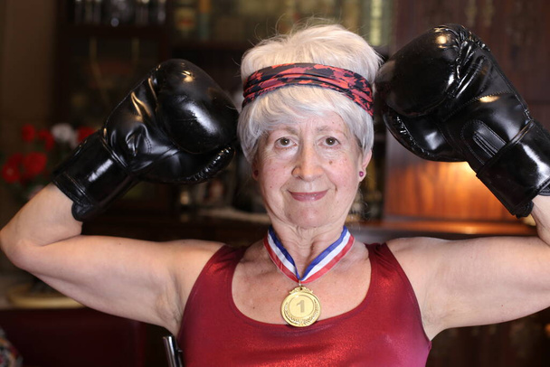 Nahaufnahme Porträt einer reifen Frau im Boxerkostüm mit Goldmedaille zu Hause, Konzept der Halloween-Feier - Foto, Bild