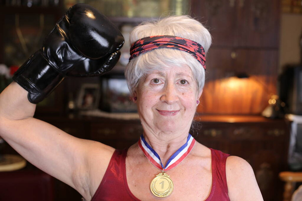 close-up portrait of mature woman in boxer costume with golden medal at home, Halloween celebration concept - Foto, afbeelding