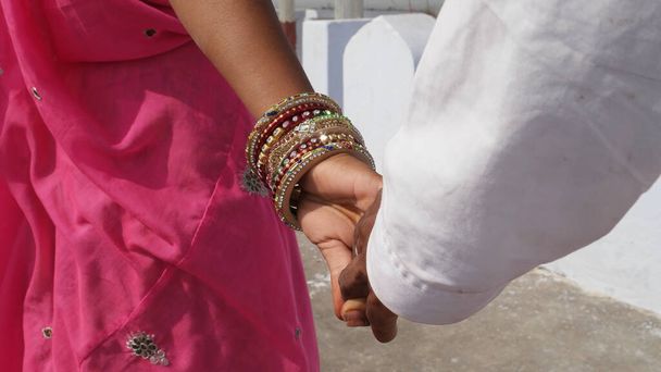 Cute young newlyweds in traditional Indian clothes holding each other hands - Zdjęcie, obraz