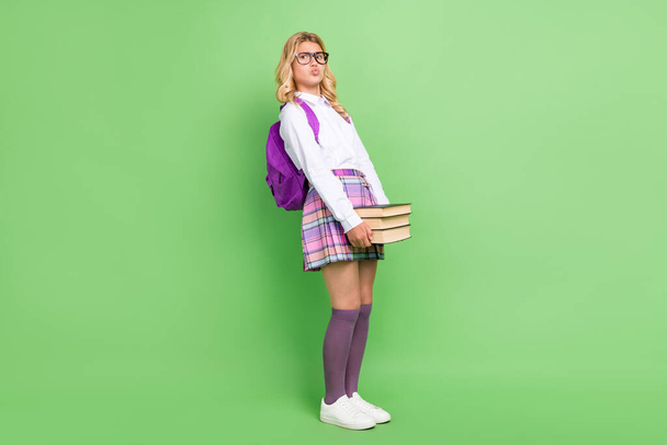 Full length body size view of attractive overwhelmed girl carrying pile book lesson isolated over green color background - Foto, immagini