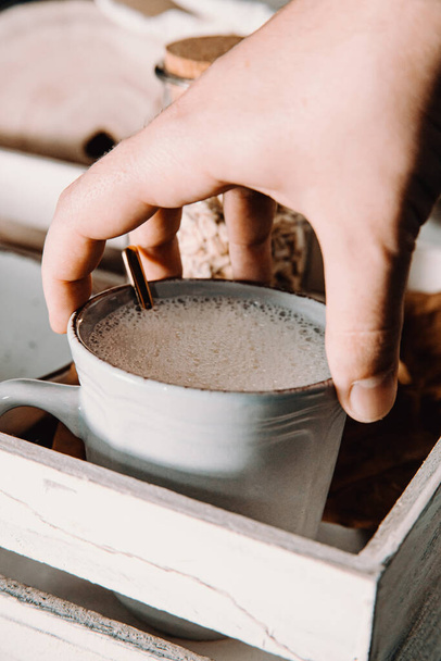 A vertical shot of a male's hand grabbing a cup of oat milk - Valokuva, kuva
