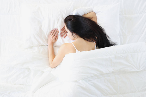 Sleeping brunette woman lies on white bed - Foto, imagen