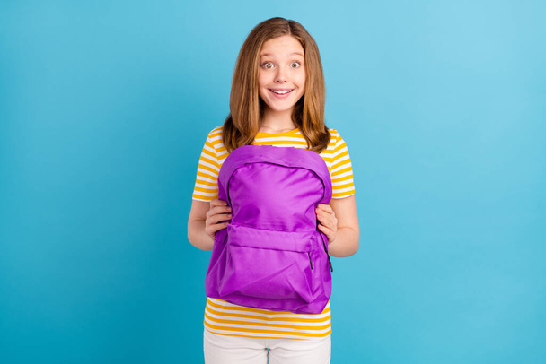 Portrait of astonished cheerful person hands hold backpack toothy smile isolated on blue color background - Foto, Imagen