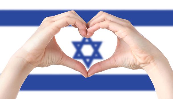 Les mains qui font cœur contre le drapeau national d'Israël - Photo, image