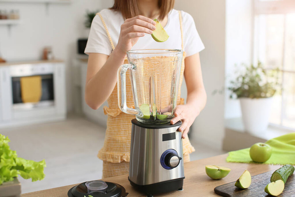 Молодая женщина готовит здоровый зеленый смузи на кухне - Фото, изображение