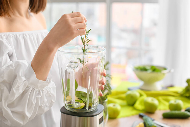 Young woman preparing healthy green smoothie in kitchen, closeup - Foto, immagini