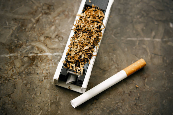 Το μηχάνημα γεμίσματος τσιγάρων με καπνό. 'δειος αναστεναγμός. Καπνός από Rossypany στο τραπέζι. Σπιτική παραγωγή τσιγάρων - Φωτογραφία, εικόνα