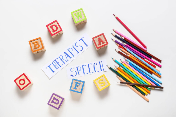 Text SPEECH THERAPIST mit Würfeln und Bleistiften auf weißem Hintergrund - Foto, Bild