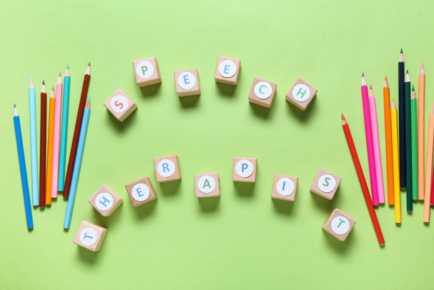 Cubes with text SPEECH THERAPIST and pencils on color background - 写真・画像