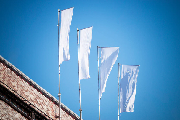 Tři prázdné bílé vlajky na vlajkových stožárech proti zatažené modré obloze s perspektivou, firemní vlajka maketa na reklamní logo, text nebo symbol, firemní identita vlajka šablony s kopírovacím prostorem - Fotografie, Obrázek