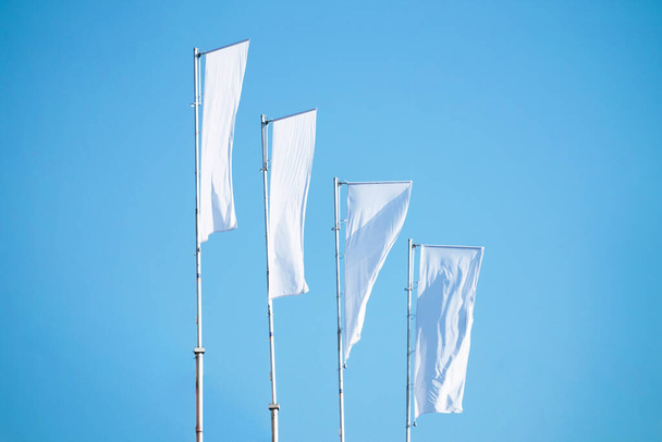 Τρεις κενές λευκές σημαίες σε κοντάρια σημαίας κατά συννεφιασμένο μπλε ουρανό με προοπτική, εταιρική σημαία mockup στο λογότυπο αγγελία, κείμενο ή σύμβολο, εταιρεία πρότυπο σημαία ταυτότητας με αντίγραφο χώρο - Φωτογραφία, εικόνα