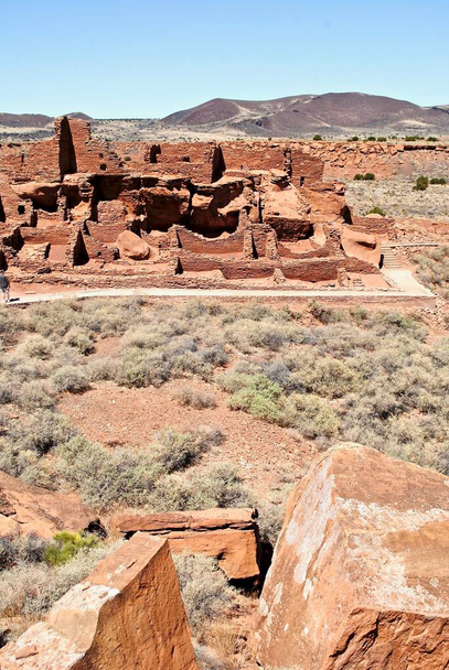 Wupatki National Monument und das Wupatki (hohes Haus) Pueblo. Die Wände des Wohnhauses wurden aus dünnen, flachen Blöcken des örtlichen Moenkopi-Sandsteins gebaut, was dem Pueblo seine markante rote Farbe verleiht.. - Foto, Bild