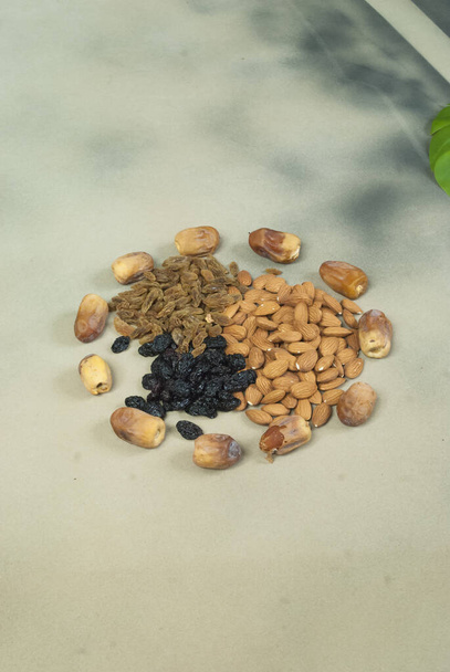 mix dry fruits nuts around dates isolated almonds black and brown raisins(kishmish) - Photo, Image