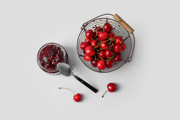Jar of tasty cherry jam on light background - Photo, Image
