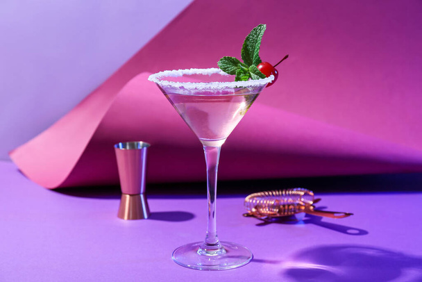 Glass of tasty cosmopolitan cocktail, shaker and strainer on color background - Photo, Image