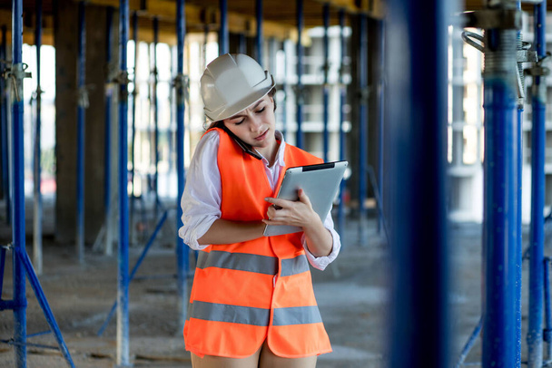 Female construction engineer. Architect with a tablet computer at a construction site. Young Woman looking, building site place on background. Construction concept. - Foto, afbeelding