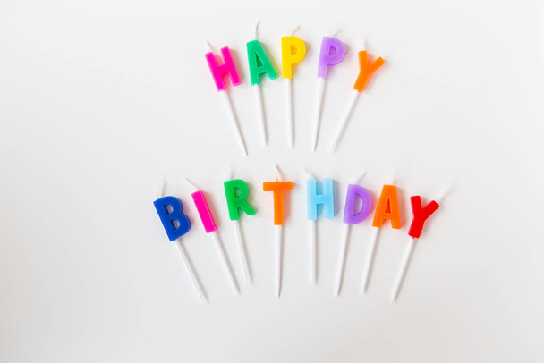 Barevné svíčky s nápisem Happy Birthday izolované na bílém pozadí. Koncept dovolené a překvapení - Fotografie, Obrázek