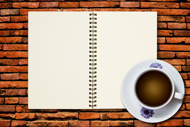 White cup of coffee and blank page notebook on brick wall background - Photo, Image