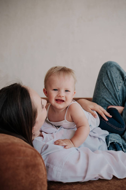 Porträt eines glücklichen Kindes, das auf einer brünetten Mutter liegt - Foto, Bild