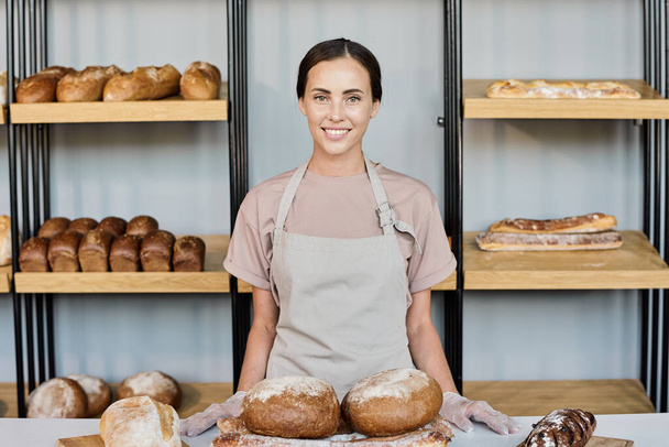 Happy young owner of bakery selling fresh bread - Foto, Bild