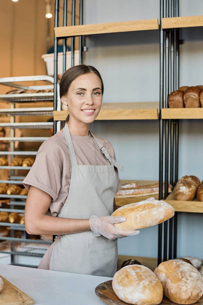 Onnellinen nuori naispuolinen leipomon omistaja myy tuoretta leipää - Valokuva, kuva
