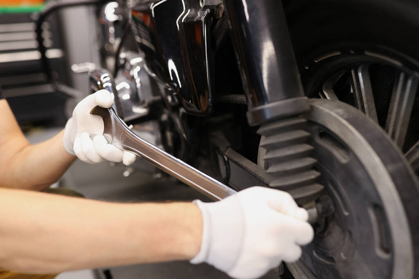 Meister schraubt Bremsscheiben am Motorrad mit Schraubenschlüssel ab - Foto, Bild