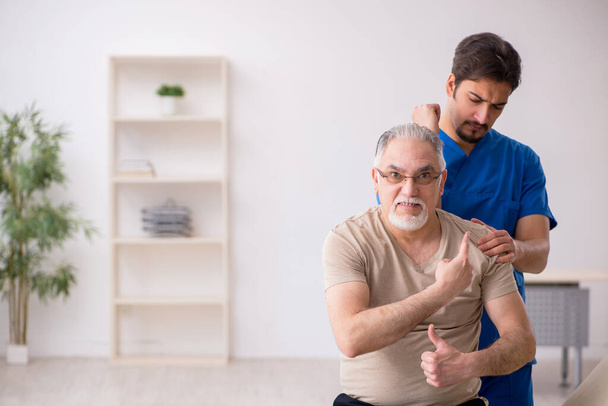 Old male patient visting young male doctor chiropractor - Photo, Image