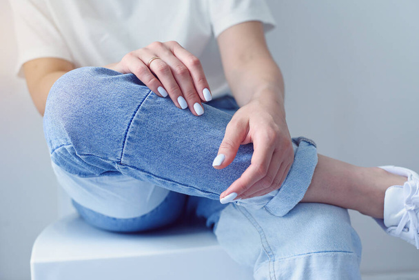 Womans hands with perfect manicure wears in denim trousers and white basic t-shirt. - Foto, Bild