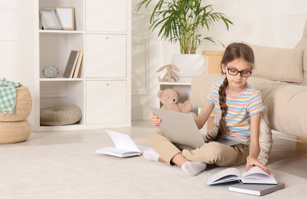 Girl with laptop and books sitting on floor at home - Фото, изображение