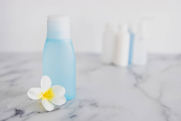 low tox and non-toxic natural beauty products conceptual image, blue lotion bottle with flower in the foreground standing out from group of other bottles   - Foto, imagen