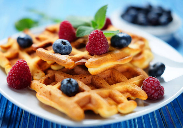 Homemade Belgian waffles served with fresh berries on white plate over wooden background, close up. Tasty. Sweet. - Photo, Image