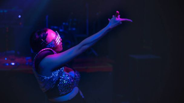 dancer in modern costume showing techno dance performance in disco and nightclub with neon and spotlight with selective focused - 写真・画像