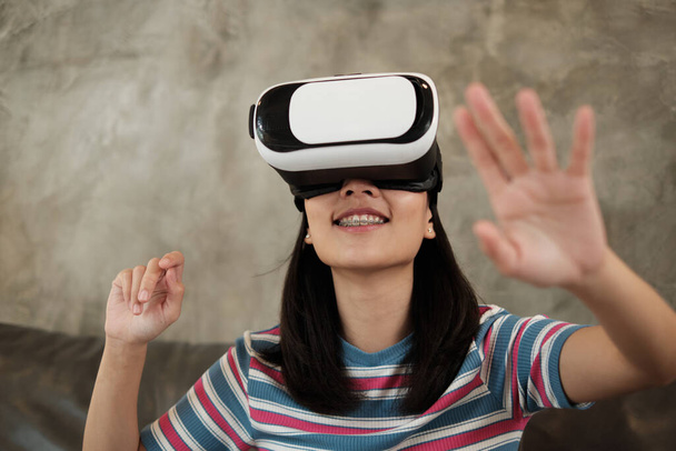 Femme asiatique avec casque de lunettes VR, regarder 3D réalité virtuelle jeu de simulation. gadget de technologie de divertissement interactif est innovant. Les gens entrent dans le cyberespace futuriste, mode de vie moderne. - Photo, image