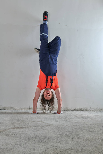 cool construction worker in orange t-shirt stands upside down - Fotografie, Obrázek