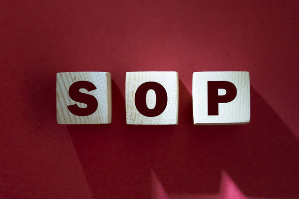 SOP - acronym from wooden blocks with letters, abbreviation SOP standard operating procedure concept, red background - Photo, Image