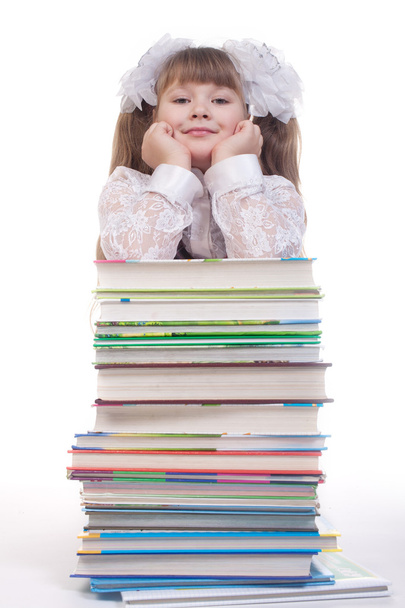 Schoolgirl leaning on a pile of books on white background - Foto, Imagem