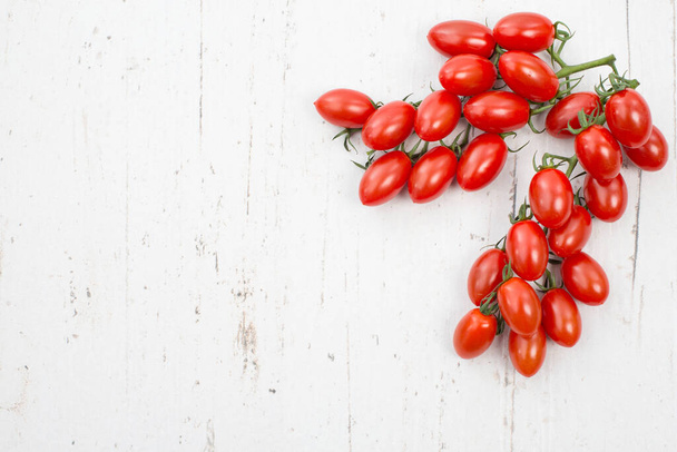 Red fresh cherry tomatoes on a white shabby background, empty copy space for text, vegan food - Foto, Bild