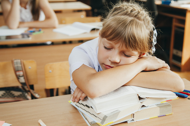 Little schoolgirl sleep in classroom near blackboard - Fotoğraf, Görsel