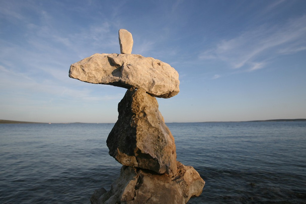 Cross, rocks stacked one one top of another on beach - Photo, Image