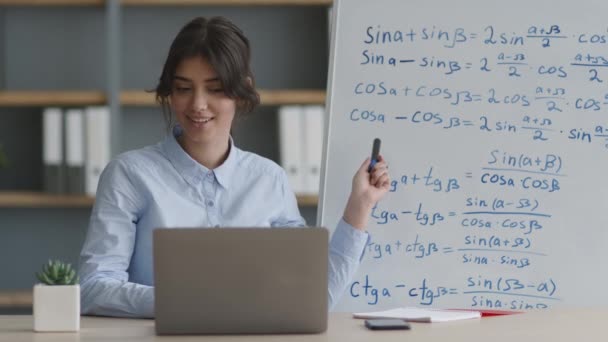 Online διδασκαλία έννοια. Νεαρή κυρία που εξασκεί την ηλεκτρονική μάθηση, εξηγώντας μαθηματικούς τύπους στο λευκό πίνακα στο μαθητή - Πλάνα, βίντεο