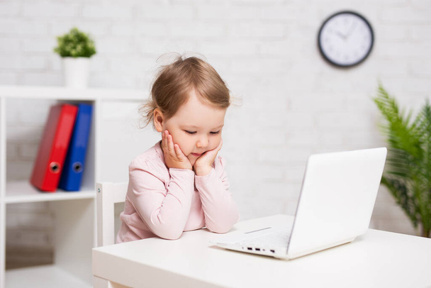childhood, education, business and technology concept - cute thoughtful little girl using laptop at home or in class room - Foto, Bild
