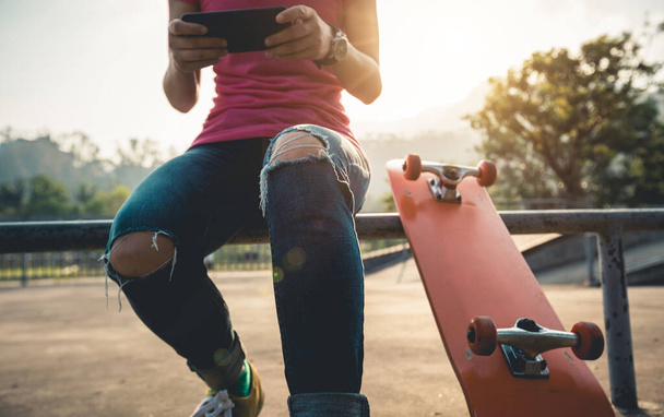 Skateboarder use mobile phone at skatepark - Valokuva, kuva
